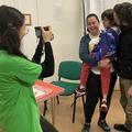 Researcher in green tshirt taking photo of family of three 