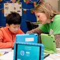 Child and researcher looking at blue ipad together