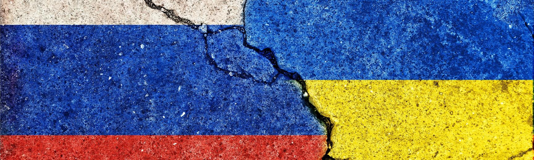 Russia and Ukraine country flags printed on cracked concrete background