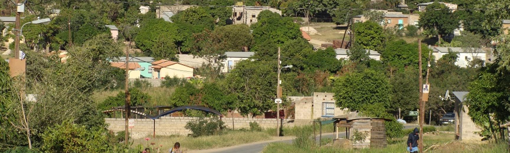 A scene of a rural south african town with overhead power cables and mountains in the background. A road runs through the middle.