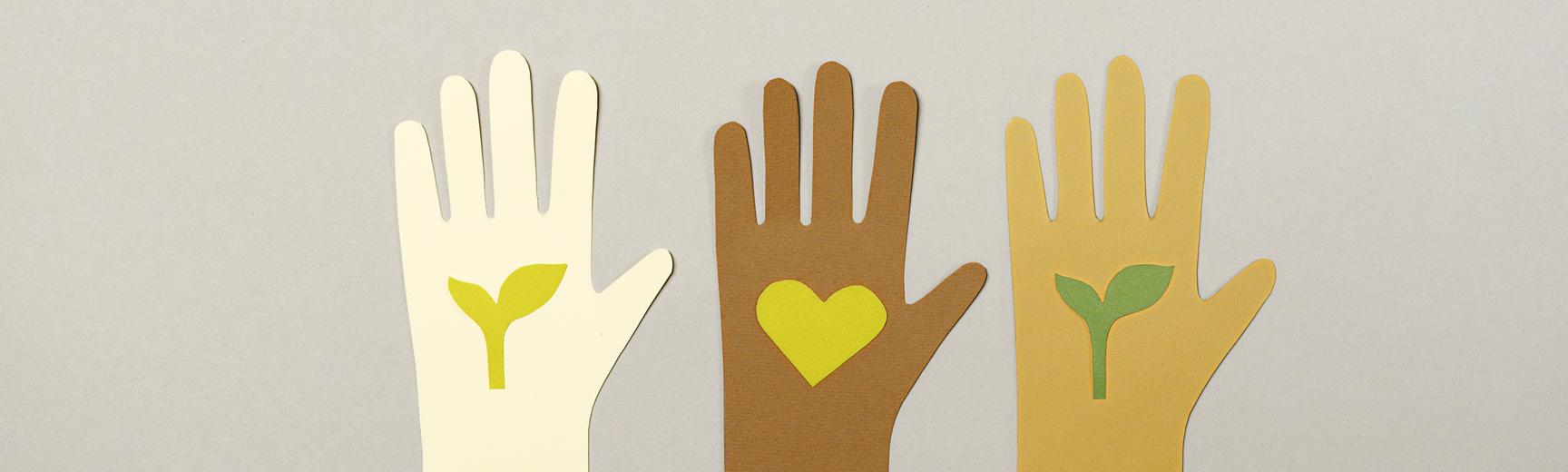 Three paper cut-outs of hands of different skin colour, each holding a paper cut out of a leaf or a heart