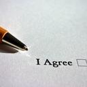 A pen rests on a sheet of paper printed with the words "I agree" and a check box