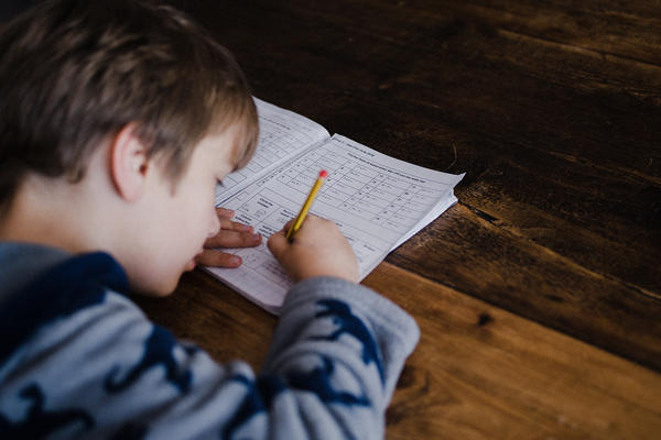 A child does his maths homework with a paper and pencil