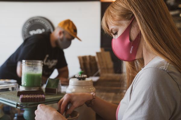 A man and woman, both wearing facemasks, are busy in a workshop