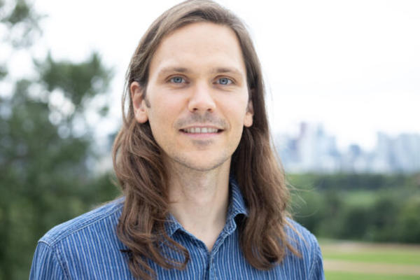 Dr Edmonds has long brown hair and is wearing a blue shirt