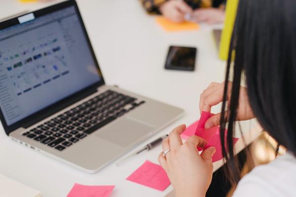 student at a desk with post-it notes and a laptop