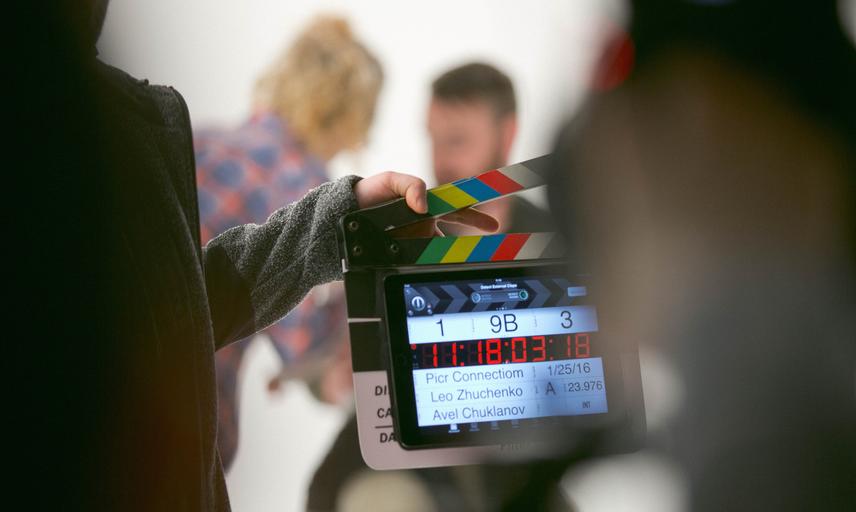 A film crew holds a clapperboard in front of actors on set