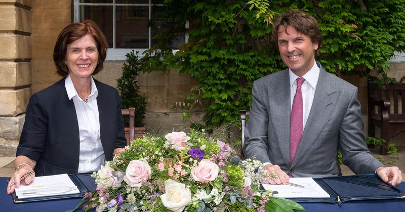 Professor Louise Richardson, Vice-Chancellor of Oxford and Hubert Keller, Co-Senior Partner of the banking group Lombard Odier, sit at a table decorated with flowers as they sign a multi-year partnership to foster sustainable finance & investment research