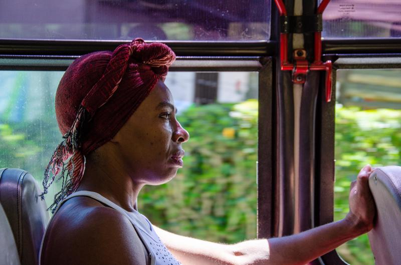 Person wearing a headscarf sitting on a bus, looking out the window.