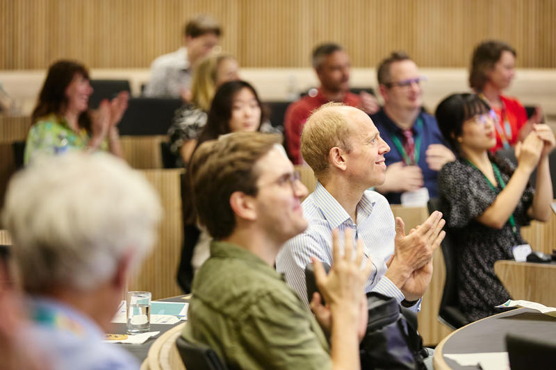 Audiences membes clap and smile at a presentation