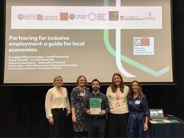 Five people stand in front of a presentation slide titled “Partnering for inclusive employment: a guide for local economies.