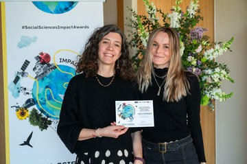 Dr Andriani Fili and Manon Louis hold their highly commended certificate.  In the background is the Impact Awards branding and a flower arrangement.