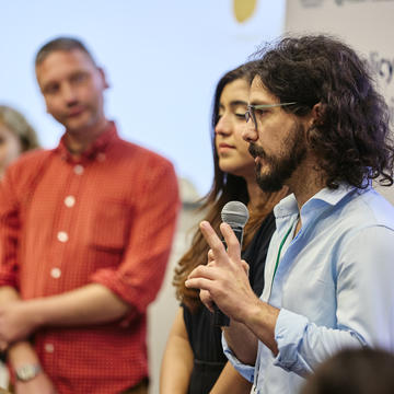 An LPL Fellow holding a microphone presents to an audience 
