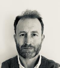 Dr Timothy Hodgetts A black and white photo of Dr Hodgetts. He has short hair and is wearing a dark jumper and white shirt.
