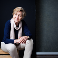 Dame Polly Courtice sits on a wooden bench