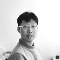 Dr Albert Songhoon Park Dr Park has short black hair and is wearing light, round-rimmed glasses and a turtleneck jumper. He is sat at a desk and turned slightly to look at the camera.