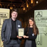 Professor Sandra Wachter and Dr Brent Mittelstadt hold their Highly Commended impact award, flanked by event branding at the awards reception