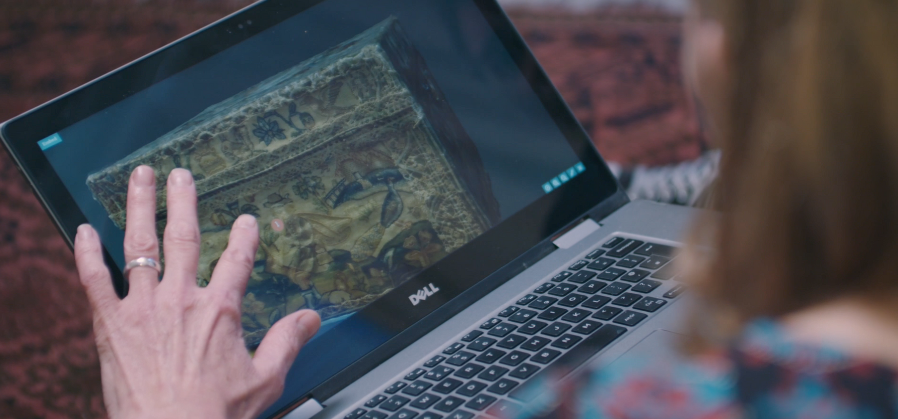 A hand points at a laptop screen with a digital platform for museum collections