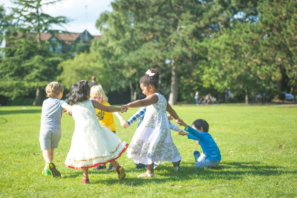children playing in a green space with trees