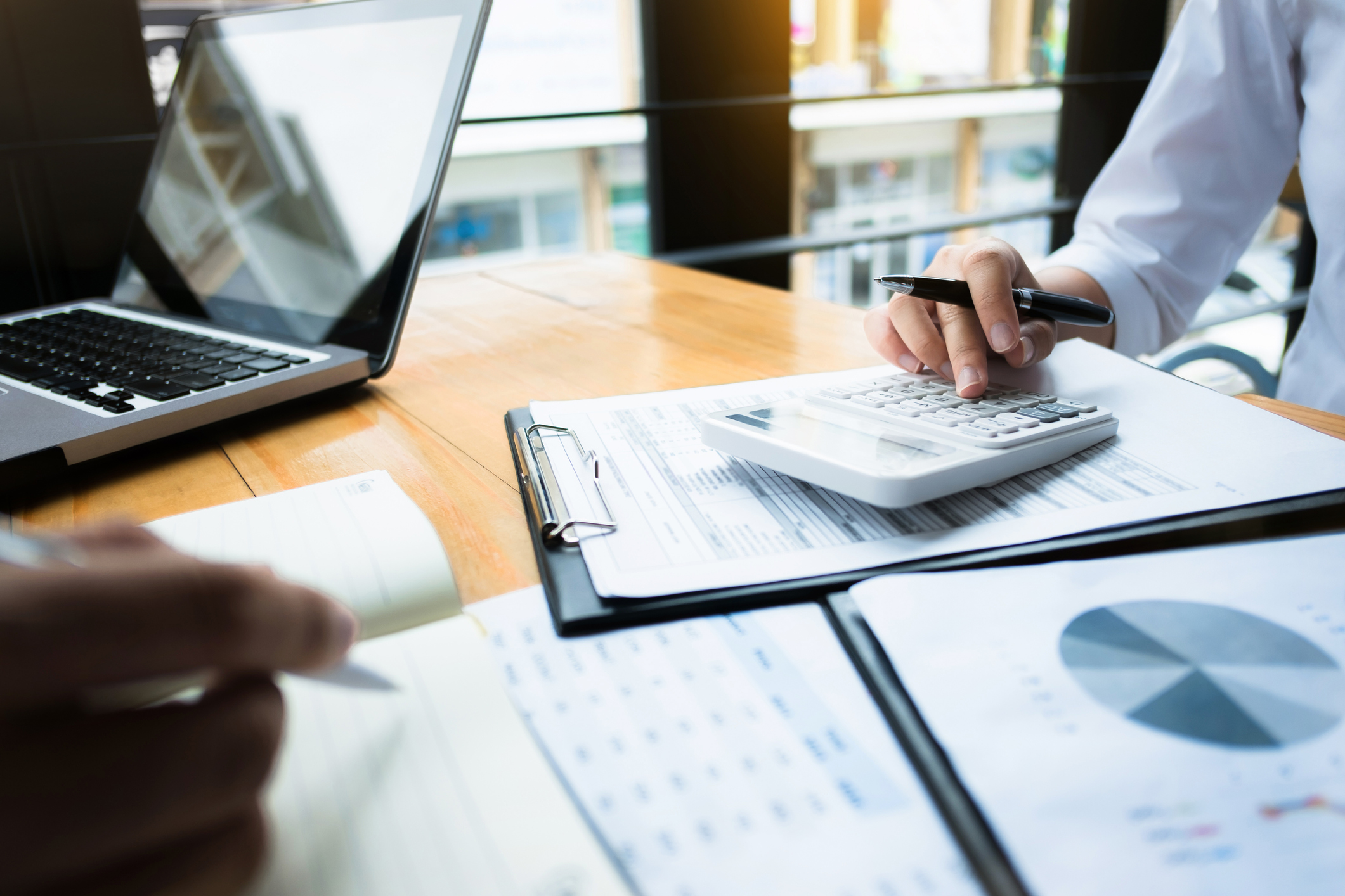 Two businessmen work over a calculator and some papers showing financial data