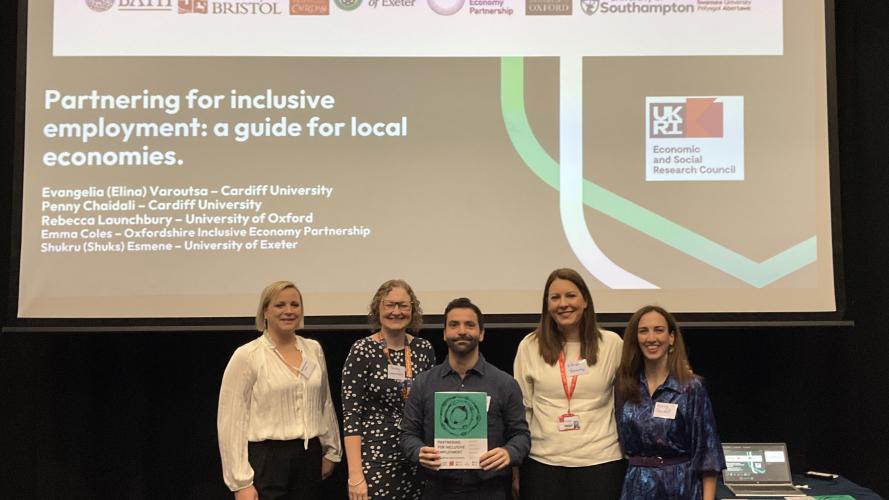 Five people stand in front of a presentation slide titled "Partnering for inclusive employment: a guide for local economies.