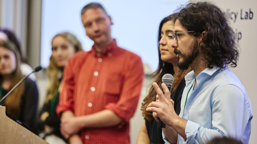 An LPL Fellow holding a microphone presents to an audience 