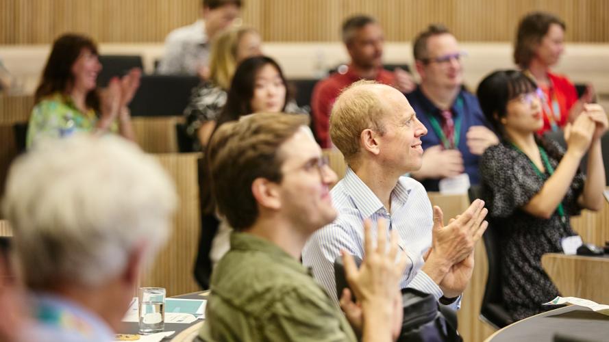 Audiences membes clap and smile at a presentation
