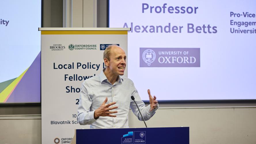 Prof Alexander Betts animatedly addresses an audience from a lectern