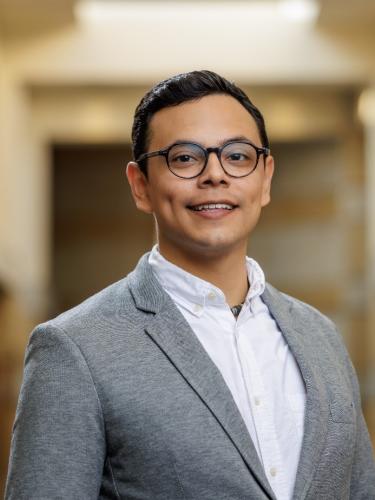 Dr. Javier Perez Sandoval wears glasses and a grey suit. He is smiling in the photo.