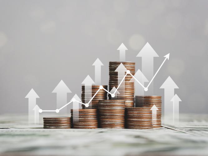 Stack of silver coins with trading charts signifying their increasing value.