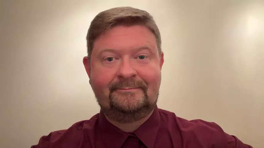 Andy has fair hair and is smiling into the camera