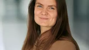 Woman with long dark hair smiles to camera