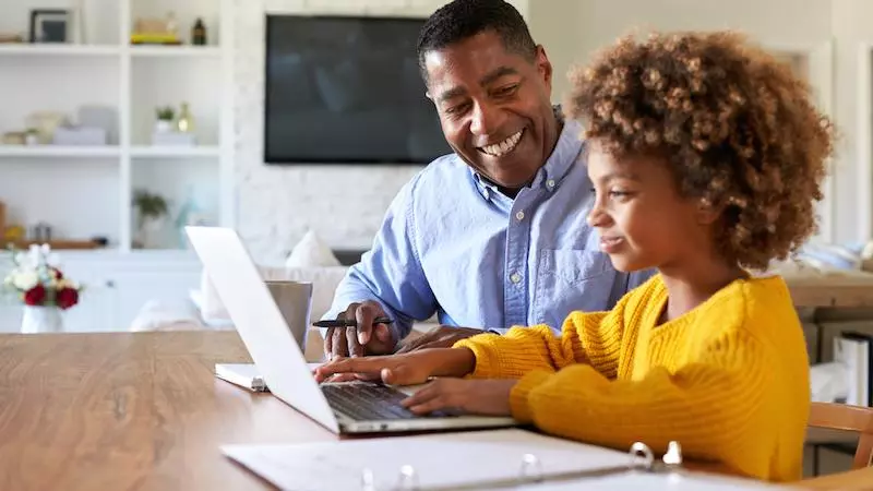 Parent home-schooling a child at a laptop