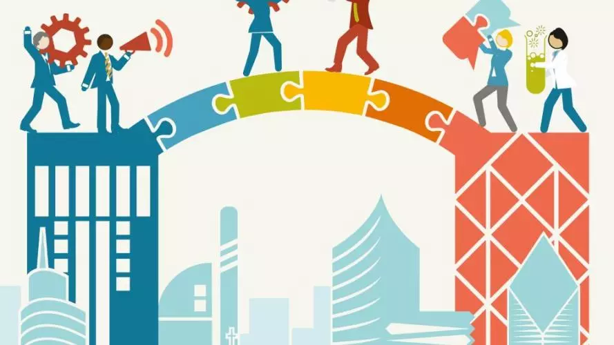 Men and women carrying objects such as a cog, a megaphone, a lightbulb, jigsaw pieces and a test tube with green liquid in, over a jigsaw bridge linking to buildings.