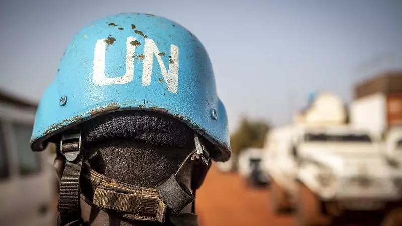 A person wears a blue UN Peacekeeper helmet