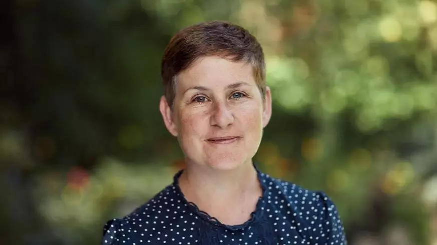 Prof Kathryn Eccles has a short pixey hair cut, wearing a dark blue top, smiling at the camera. 