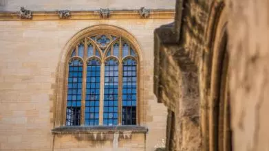 An ornate stone window on the top floor of a library building