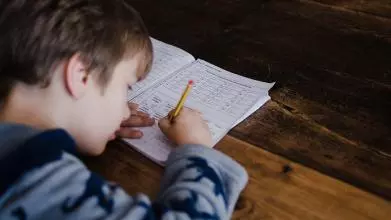 A child does his maths homework with a paper and pencil