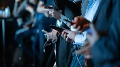 A group of men in suits all checking their smart devices
