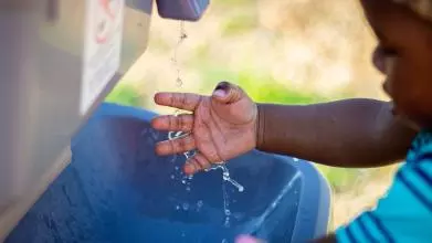 A young child washes their hands