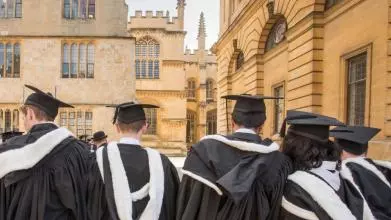 Students wearing gowns and mortar boards outside the Sheldonian