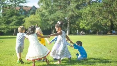 children playing in a green space with trees