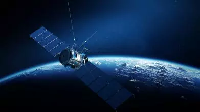 Communications satellite orbiting Earth with sunrise in space