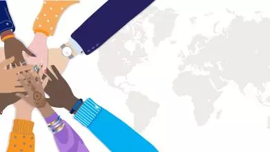 A diverse, multinational group of people holding hands together in circle over a world map background