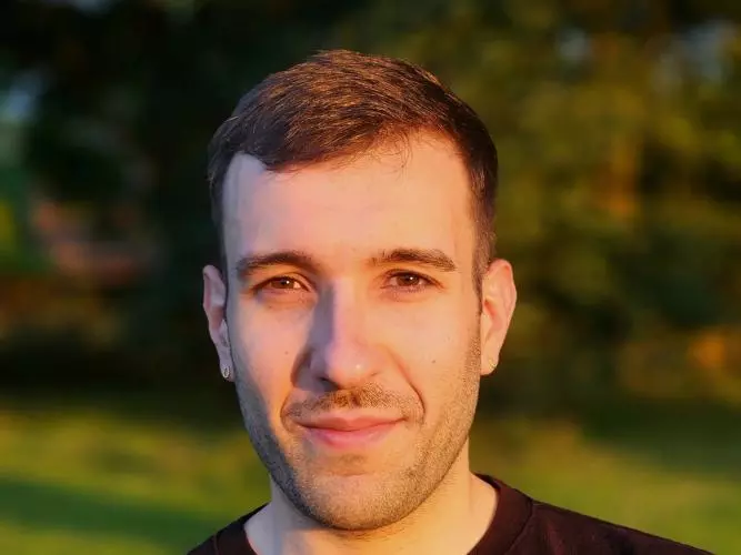 Dr Ippolito has short brown hair and brown eyes. He is wearing a dark jumper, and is standing outside. 