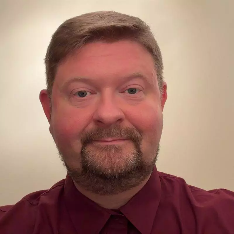 Andy has fair hair and is smiling into the camera