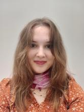 White woman with light brown hair and orange dress