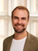 White man smiling with beige jacket