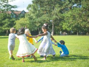 children playing in a green space with trees