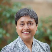 Nandini gooptu stands outside against a leafy bush